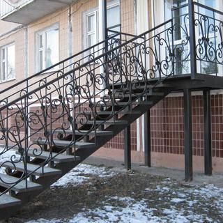 Металлическая лестница для улицы с большой площадкой и кованными перилами.